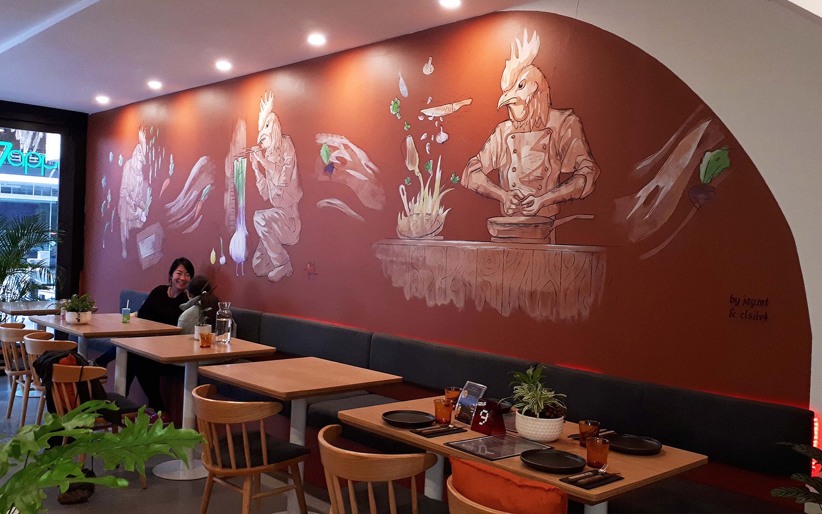 Clientes felices dentro de un restaurante en Barcelona con mural artístico después de una mejora visual